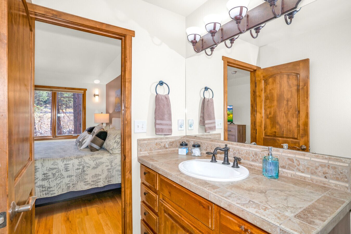 A bathroom with a large mirror, a sink, and a vanity with drawers.