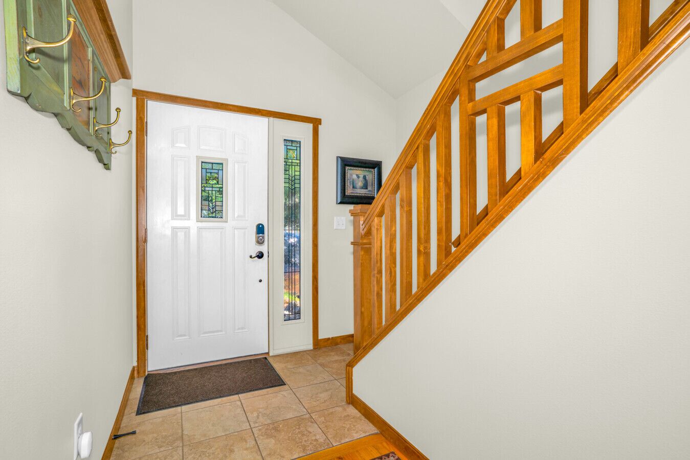 A hallway with a white door, a wooden staircase, and a small rug.