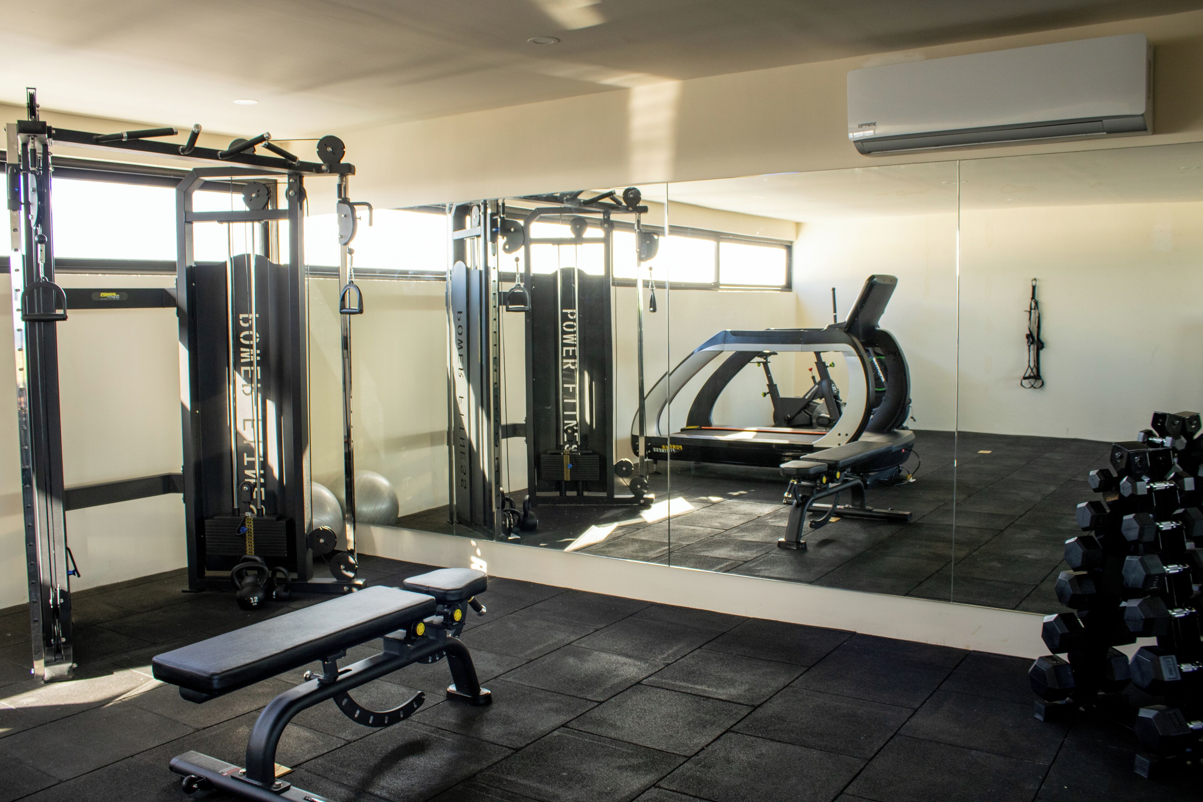 A gym with weightlifting equipment, a bench, and a treadmill.