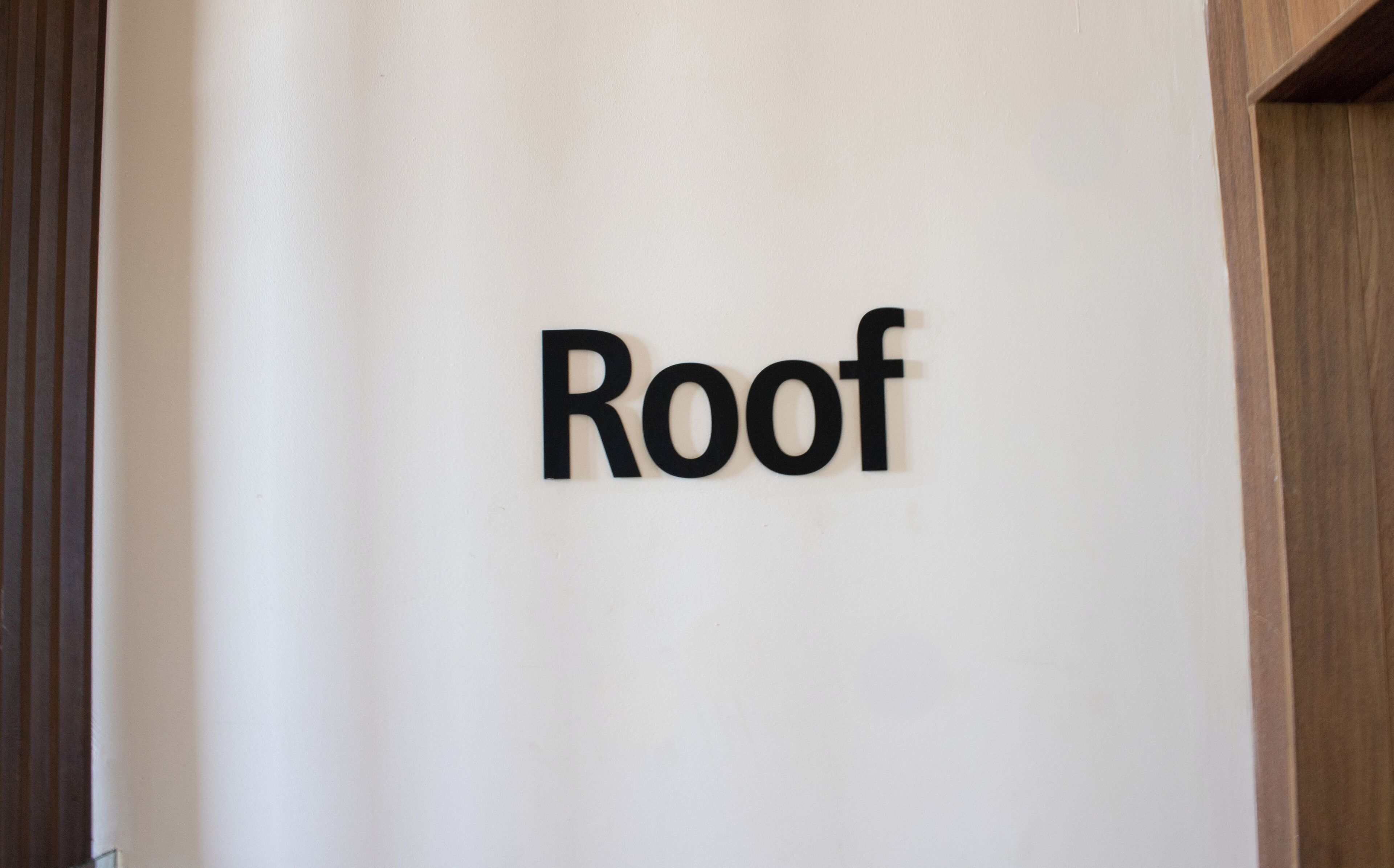 A sign with the word "Roof" on a white wall.