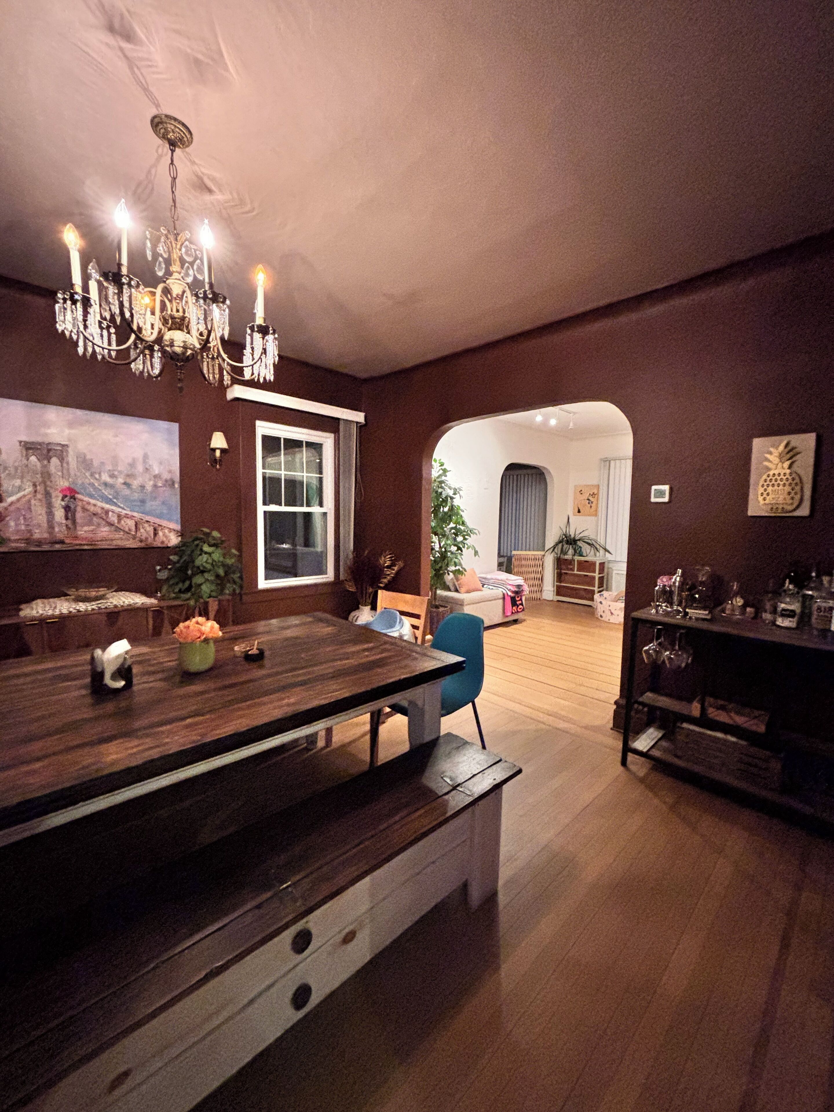 Un salon spacieux avec une table à manger en bois, un lustre et une grande fenêtre.