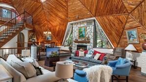 Ein geräumiges Loft mit hohen Holzbalkendecken, einem Kamin und einer gemütlichen Sitzecke mit Sofa und Sesseln.