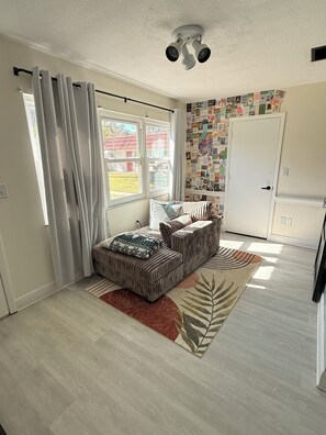 A room with a sofa set, a patterned rug, a ceiling light fixture, and a wall with a collage of pictures. - Spacious 2 BR + Sunroom - Near Beaches and Downtown (St. Petersburg)