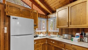 A kitchen with wooden cabinets, a white refrigerator, a sink, and a toaster. - Mama Bear's Cozy Cabin - Fireplace, Central Heat, Spacious Deck (Sugarloaf)