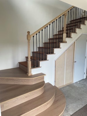 A wooden staircase with black balusters and a white wall.