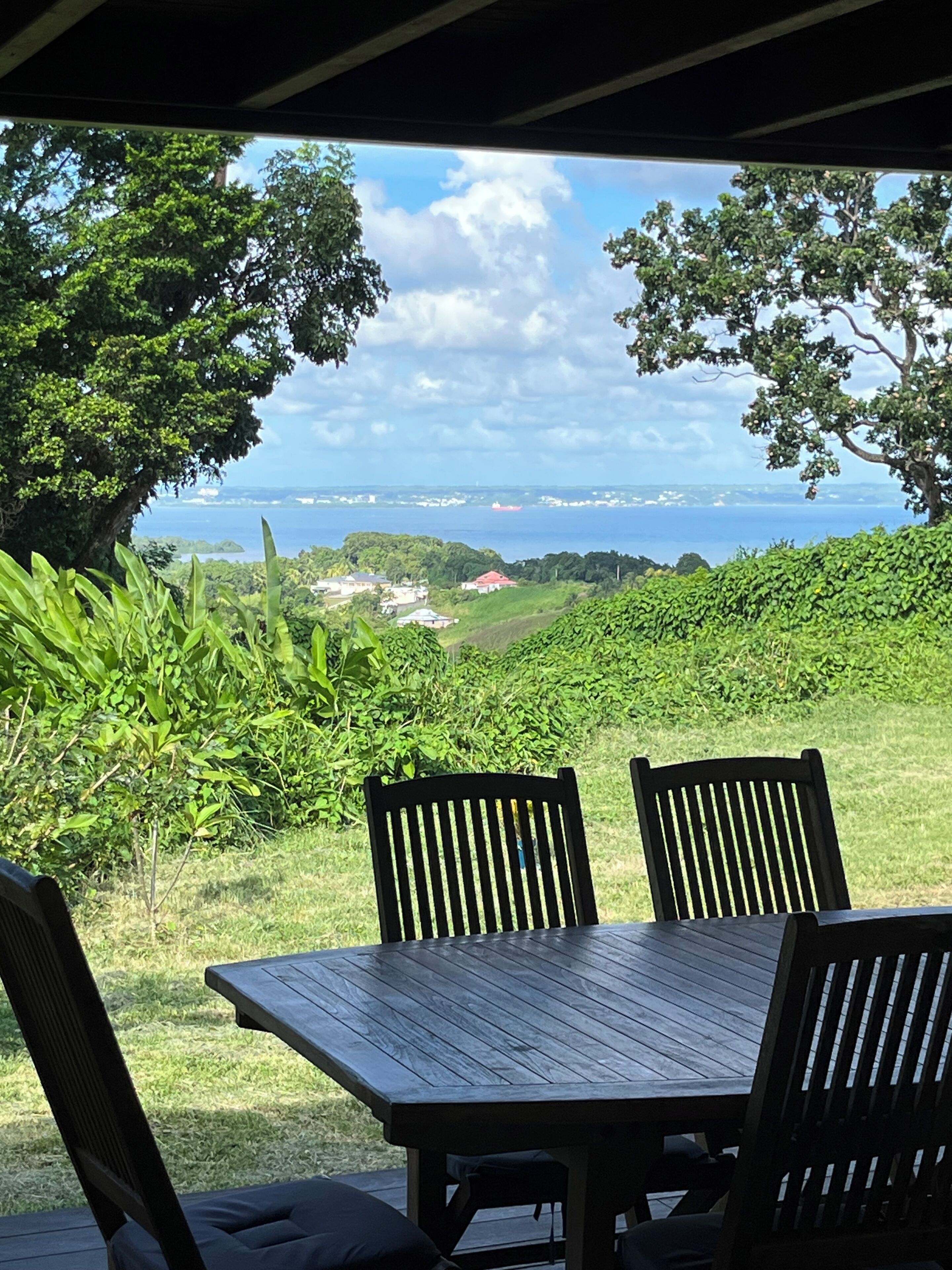 Ein Tisch mit Stühlen im Freien, mit Blick auf eine Küstenlandschaft und entfernte Gebäude.