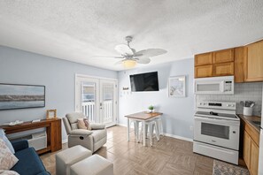 Une cuisine moderne avec des appareils électroménagers blancs, des meubles de rangement en bois et un coin repas comprenant une table et des chaises.