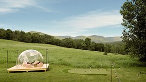 A golf course with a dome structure and a wooden platform. - Le View Chalet- HotTub, Sauna, Fire Pit, Geodome (Maplecrest)