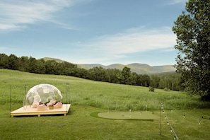 A golf course with a dome structure and a wooden platform. - Le View Chalet- HotTub, Sauna, Fire Pit, Geodome (Maplecrest)
