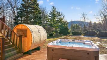 Une terrasse en bois avec un jacuzzi et un sauna.