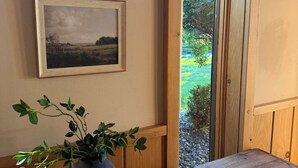 A wooden bench with a potted plant, two framed pictures on the wall, and a window with a view of greenery. - Le View Chalet- HotTub, Sauna, Fire Pit, Geodome (Maplecrest)