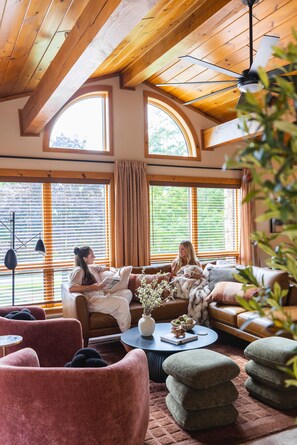 Un salon chaleureux avec un haut plafond, de grandes fenêtres et une cheminée.