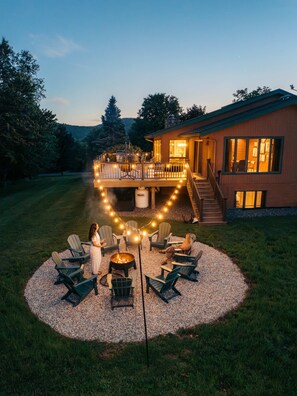 A circular outdoor seating area with Adirondack chairs and a fire pit, surrounded by a gravel circle.