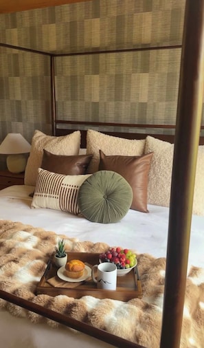 A bed with multiple pillows, a tray with food and a mug, and a lamp on a nightstand. - Le View Chalet- HotTub, Sauna, Fire Pit, Geodome (Maplecrest)