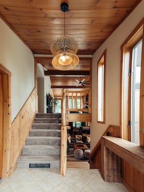 A wooden staircase with a ceiling fan and a hanging light fixture.