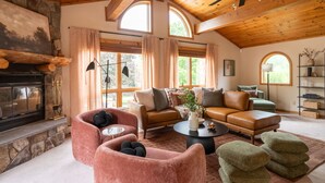 A cozy living room with a fireplace, leather sofas, a coffee table, and a ceiling fan. - Le View Chalet- HotTub, Sauna, Fire Pit, Geodome (Maplecrest)