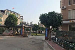 Una entrada protegida con un pabellón tradicional, un monumento de piedra grande y un edificio con una bandera.