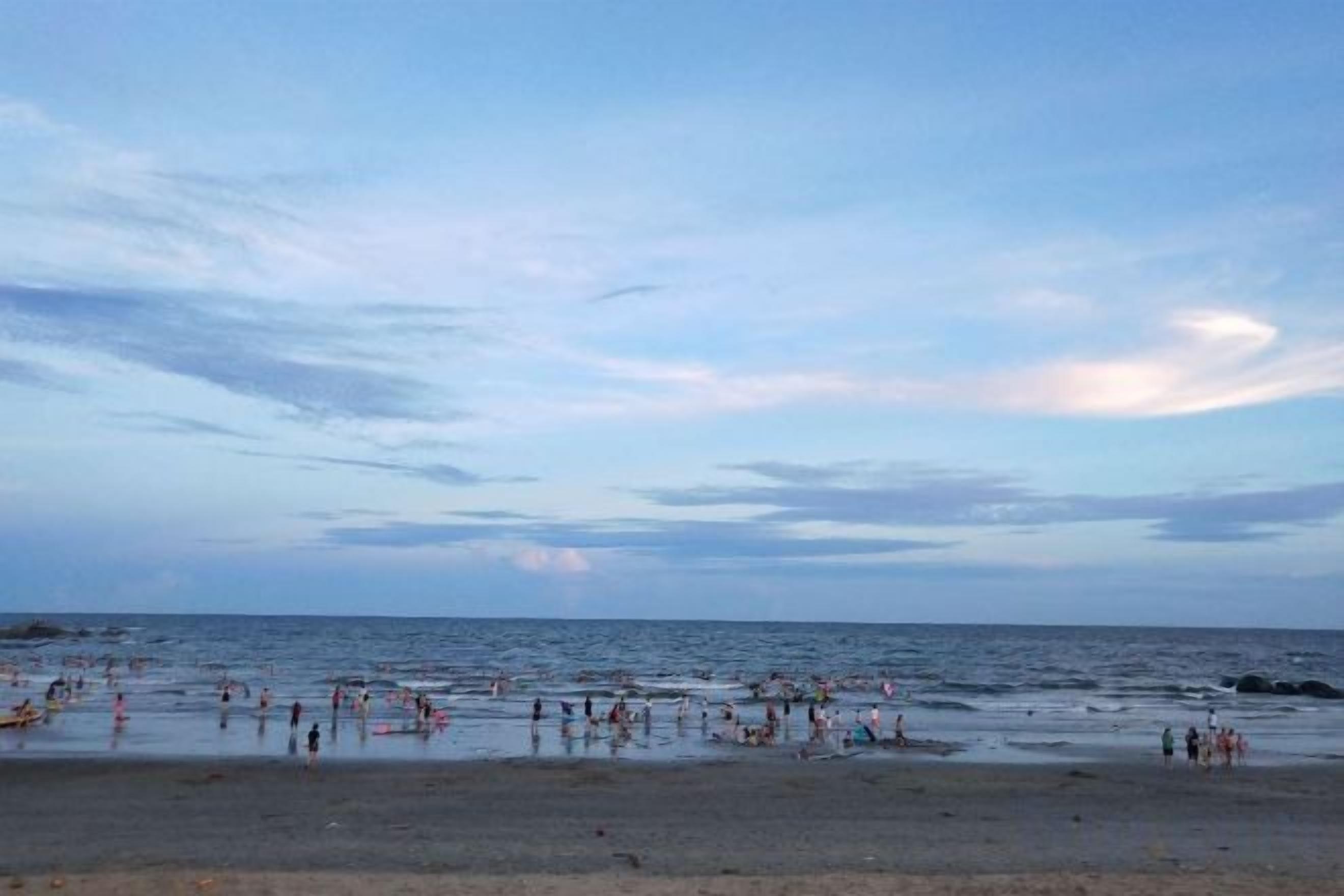 A beach with people and a calm sea.
