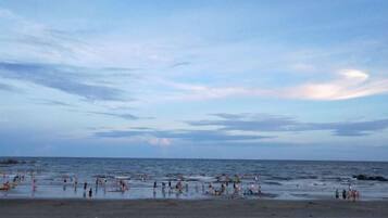 A beach with people and a calm sea.