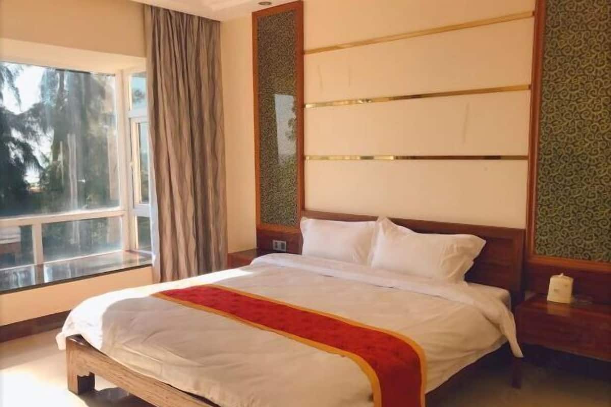Ein Hotelzimmer mit einem großen Bett, einem Fenster mit Vorhängen und einer Wand mit Musterpapier.