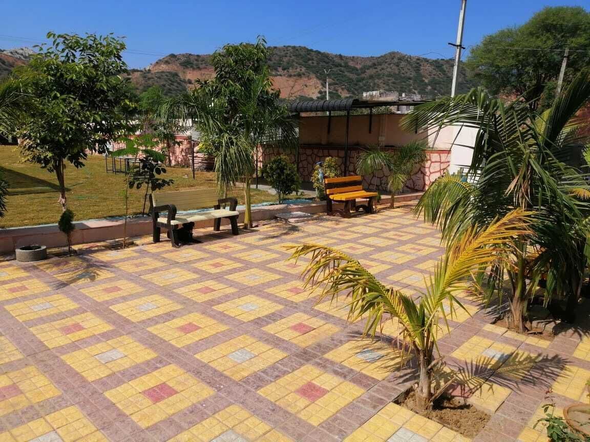 A courtyard with a tiled floor, benches, and palm trees.