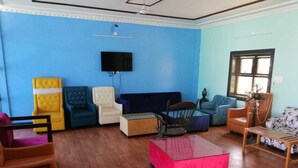 Una sala de estar con una pared azul, un televisor de pantalla plana sobre un sofá y una mesa de centro de madera en el centro.