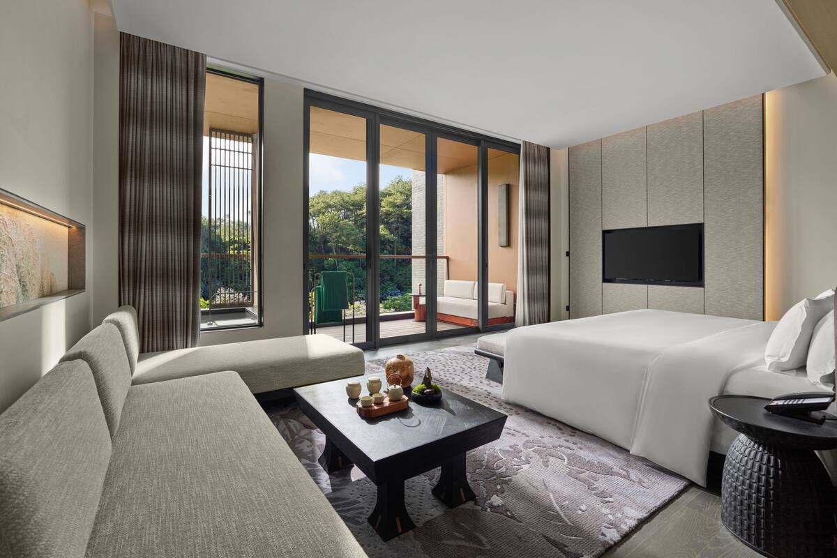 Una habitación de hotel moderna con sofá, una mesa de centro, cama y televisor.