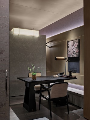 Un intérieur moderne avec une table et des chaises en bois foncé, une plante en pot et une lampe fixée au mur.
