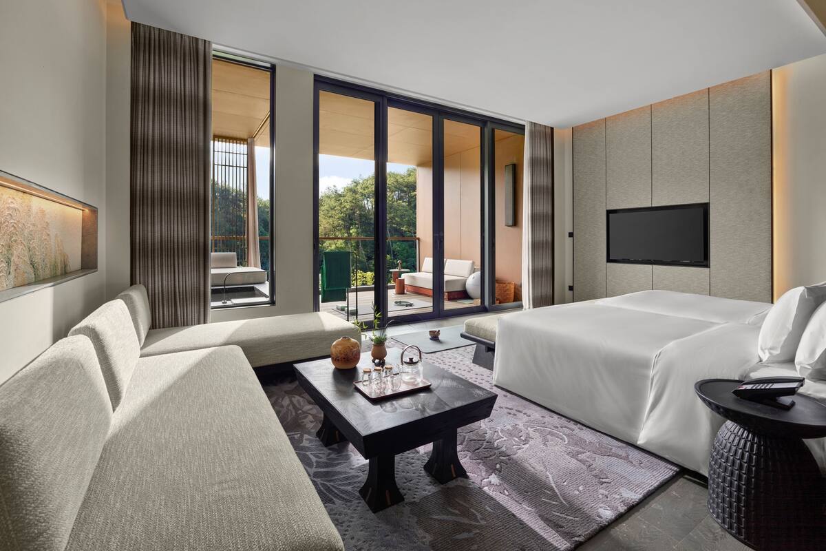 Una habitación de hotel moderna con sofá, cama, televisor de pantalla plana y vistas al exterior.