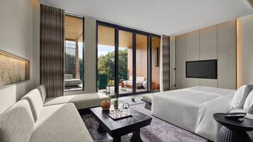 A modern hotel room with a sofa, a bed, a flat-screen TV, and a view of the outdoors.