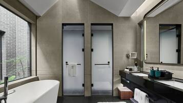 A modern bathroom with a freestanding bathtub, a large mirror, and a window with a view of a brick wall.