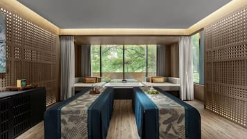 Ein modernes Zimmer mit einem langen Tisch, zwei Sitzgruppen und großen Fenstern.