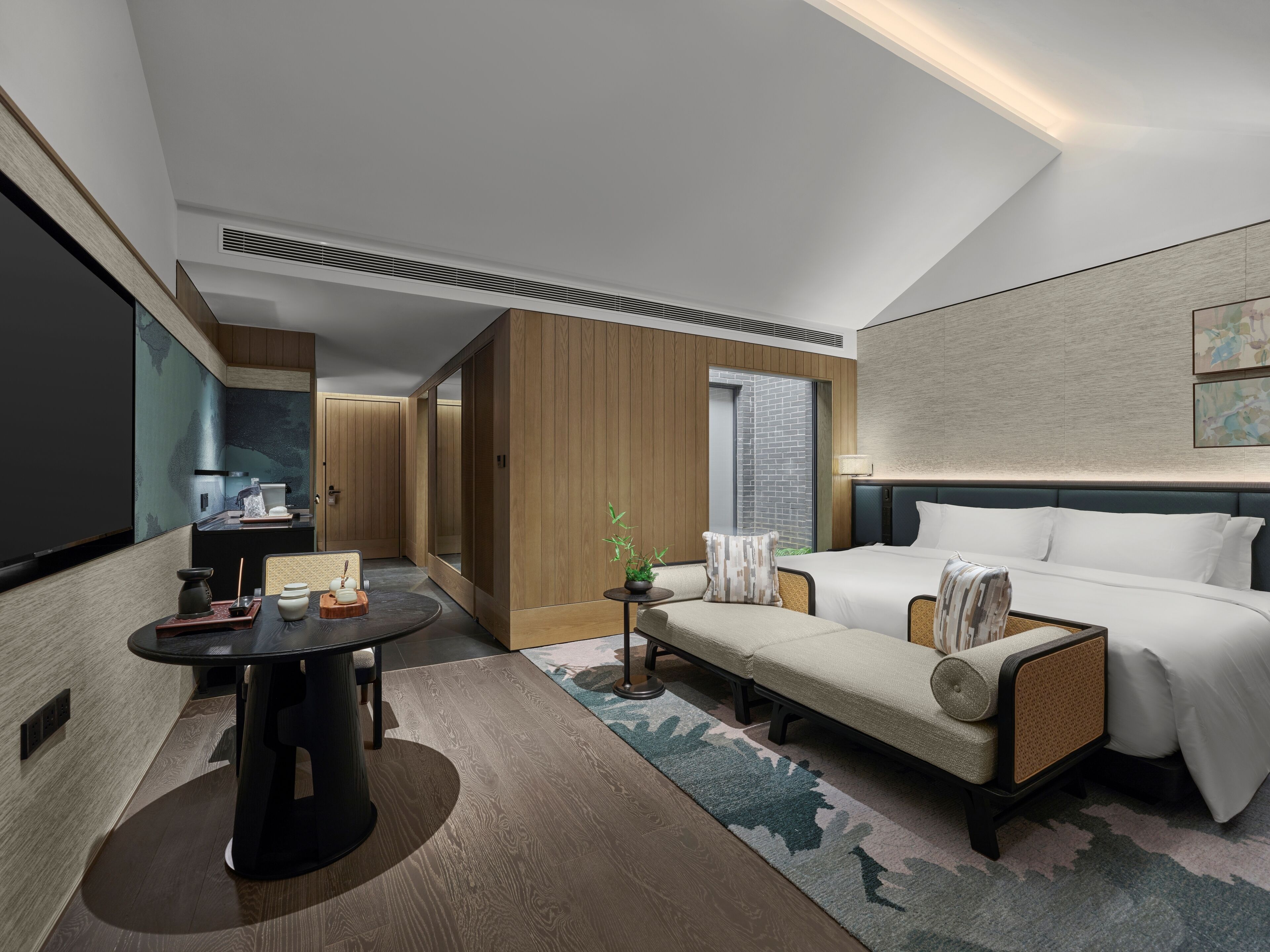 Una habitación de hotel moderna con cama, sofá, mesa de comedor y vistas al exterior.
