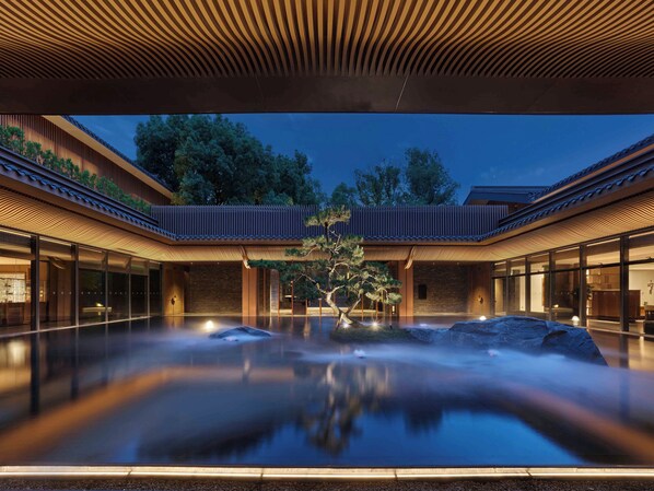 A tranquil indoor pool area with a traditional architectural design, surrounded by glass walls and a wooden ceiling. - Banyan Tree Mount Emei (Leshan)