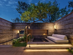 Une terrasse extérieure moderne avec un mur en briques, un banc en bois, une petite piscine et un arbre.