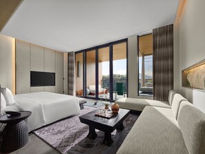A modern hotel room with a bed, sofa, flat-screen TV, and a balcony with a view. - Banyan Tree Mount Emei (Leshan)