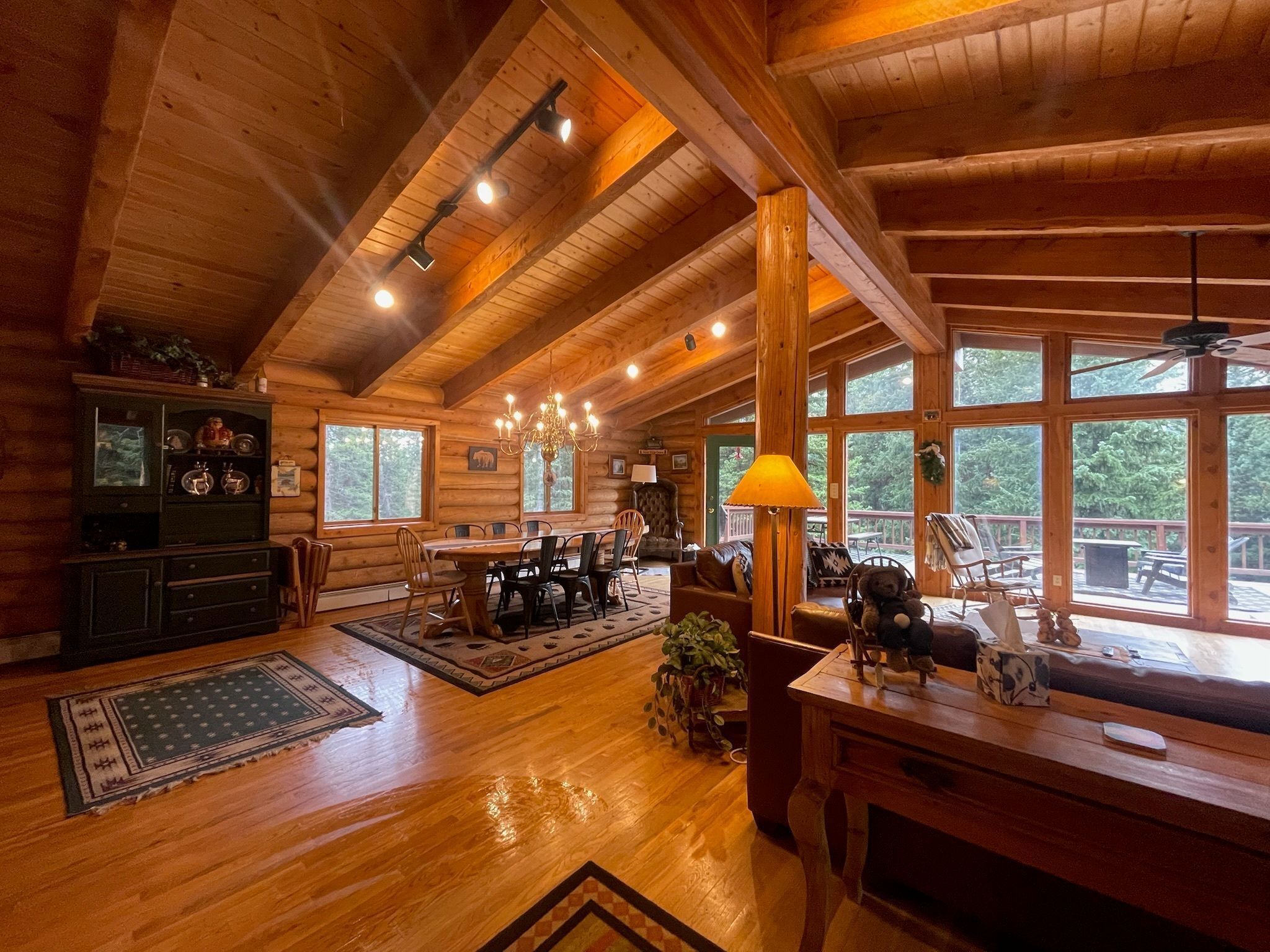 A spacious log cabin interior with a dining area, a fireplace, and large windows.