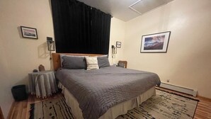 Ein Schlafzimmer mit einem Bett, einem Heizkörper, einem Teppich und einem Wandbild.