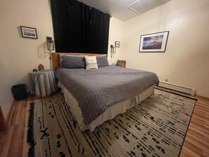 A bedroom with a bed, a radiator, a rug, and a wall-mounted picture. - Bearview Lodge Alma Colorado (Fairplay)