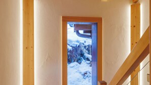 Una escalera de madera conduce a una habitación con vistas a un paisaje nevado a través de una puerta.