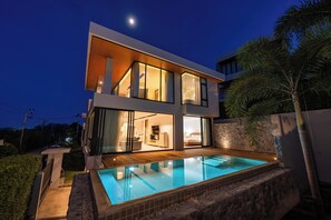 A modern two-story house with a swimming pool, large windows, and a stone wall. - Tranquil 3-Storey Villa with Private Pool (Koh Samui)