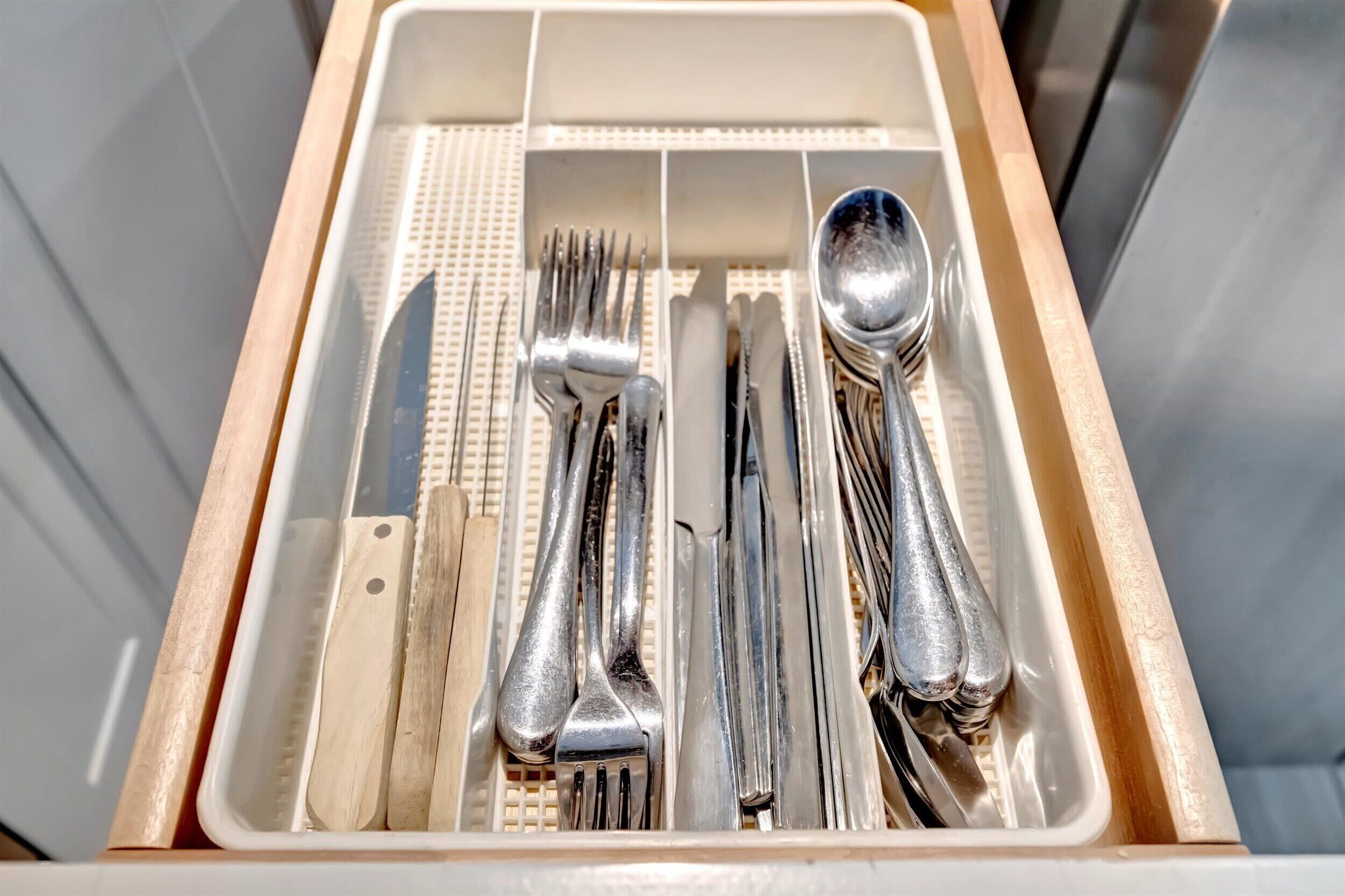 A drawer containing neatly arranged silverware, including forks, knives, and spoons.