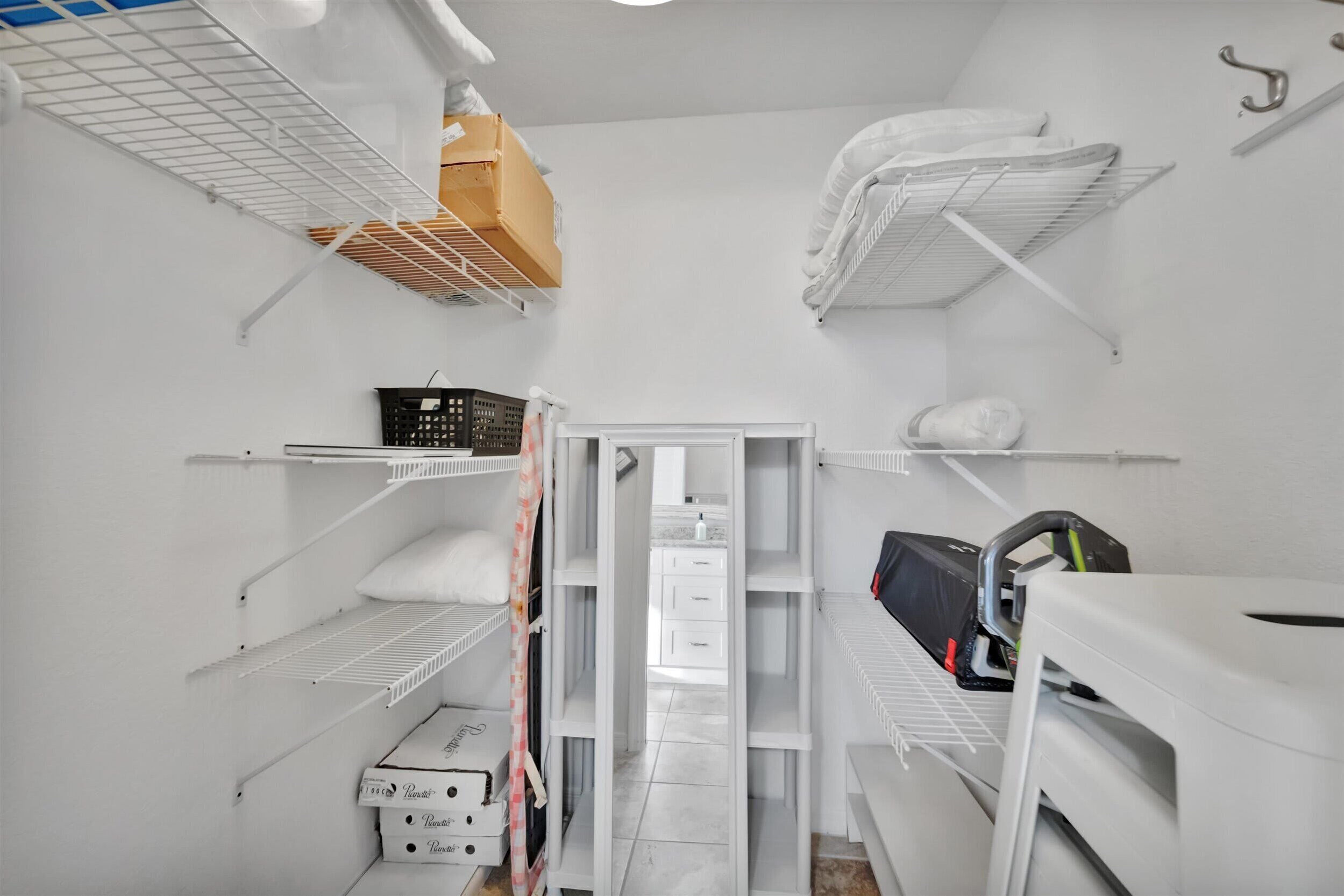 A compact storage room with white shelves, a small table, and a door leading to another area.