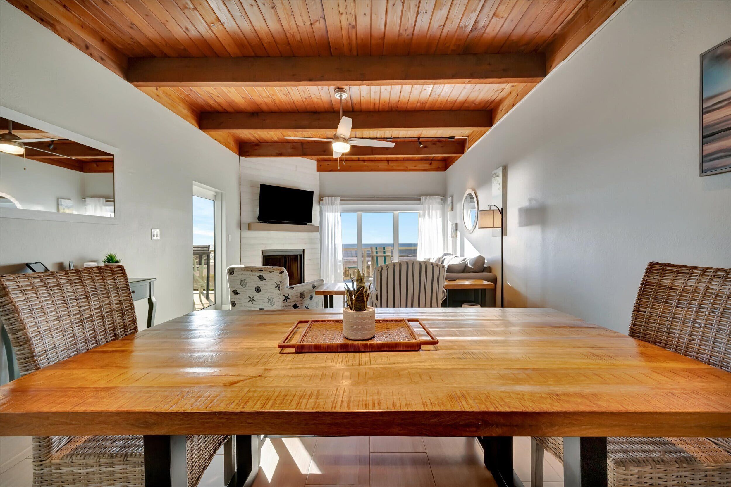 A spacious dining area with a wooden table, wicker chairs, and a ceiling fan.