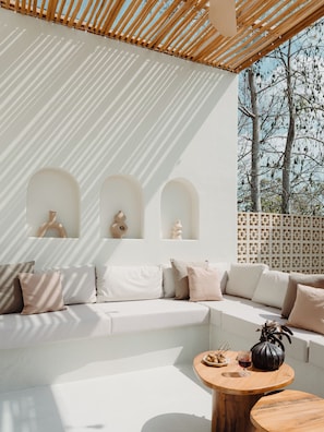 A modern outdoor seating area with a white sofa, wooden coffee table, and decorative vases.