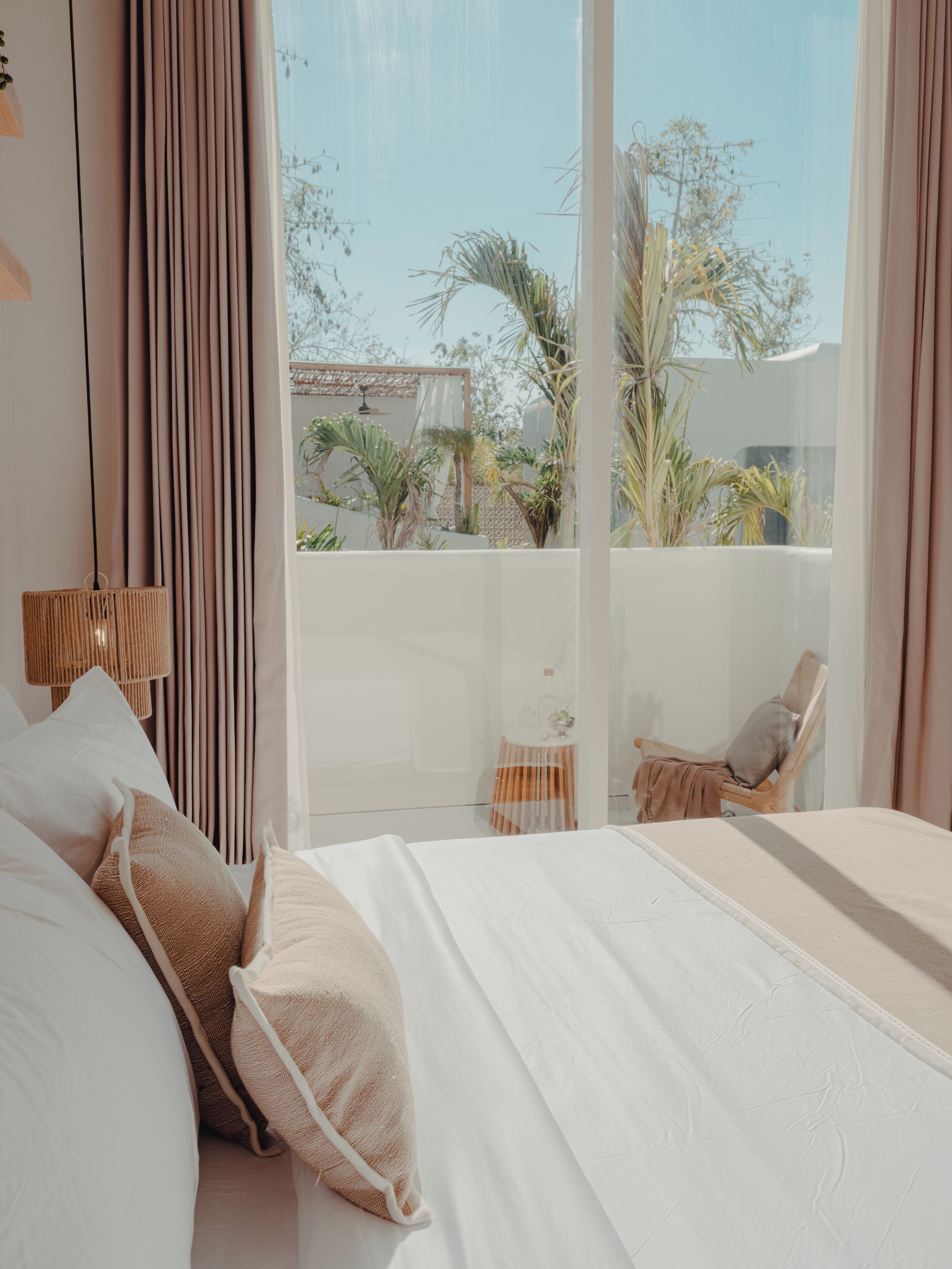 Un dormitorio con una cama grande, una silla y vistas al exterior.