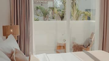 Un dormitorio con una cama grande, una silla y vistas al exterior.