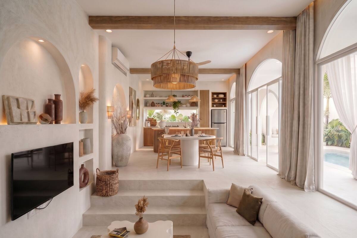 Un interior moderno con televisor, sofá, comedor, cocina y ventanas amplias.