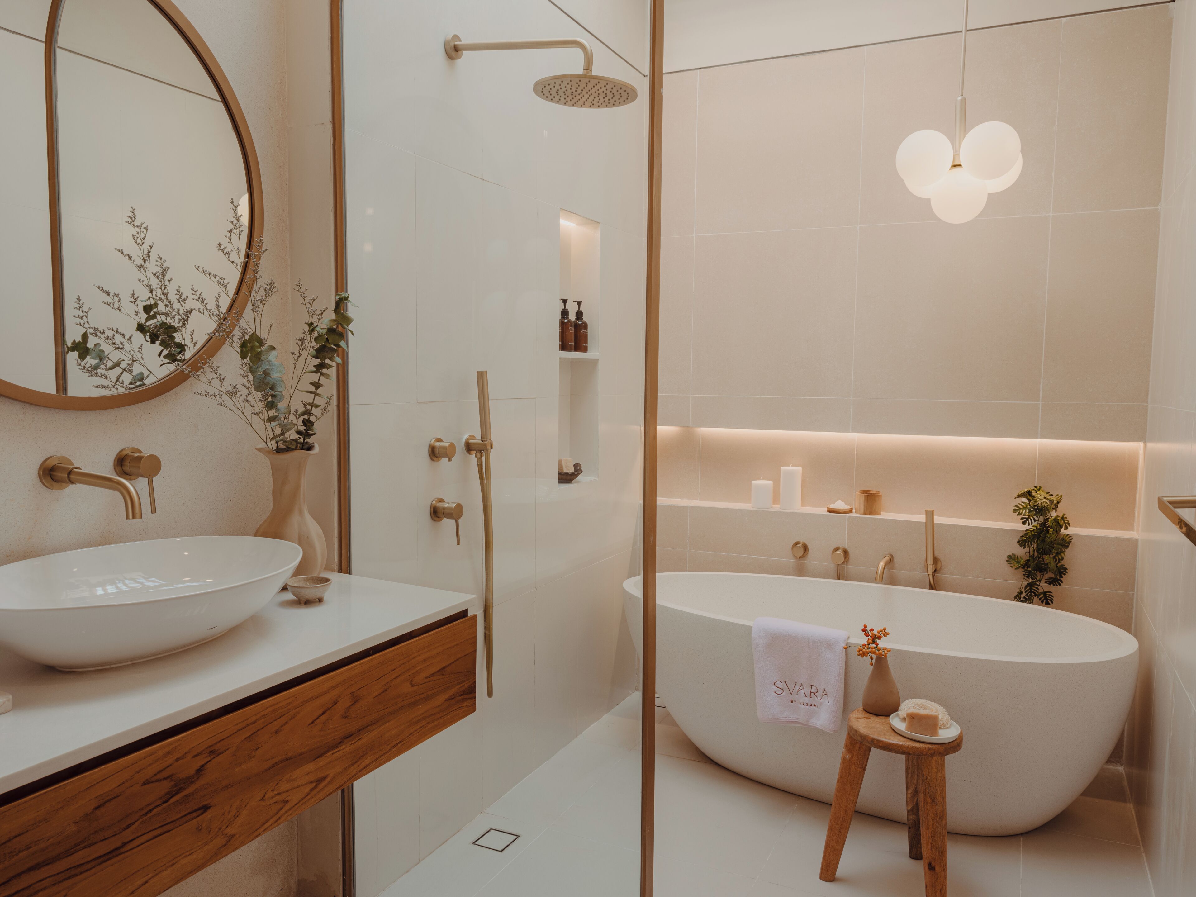 Une salle de bain moderne avec une baignoire sur pieds, un miroir rond et un meuble-lavabo en bois.