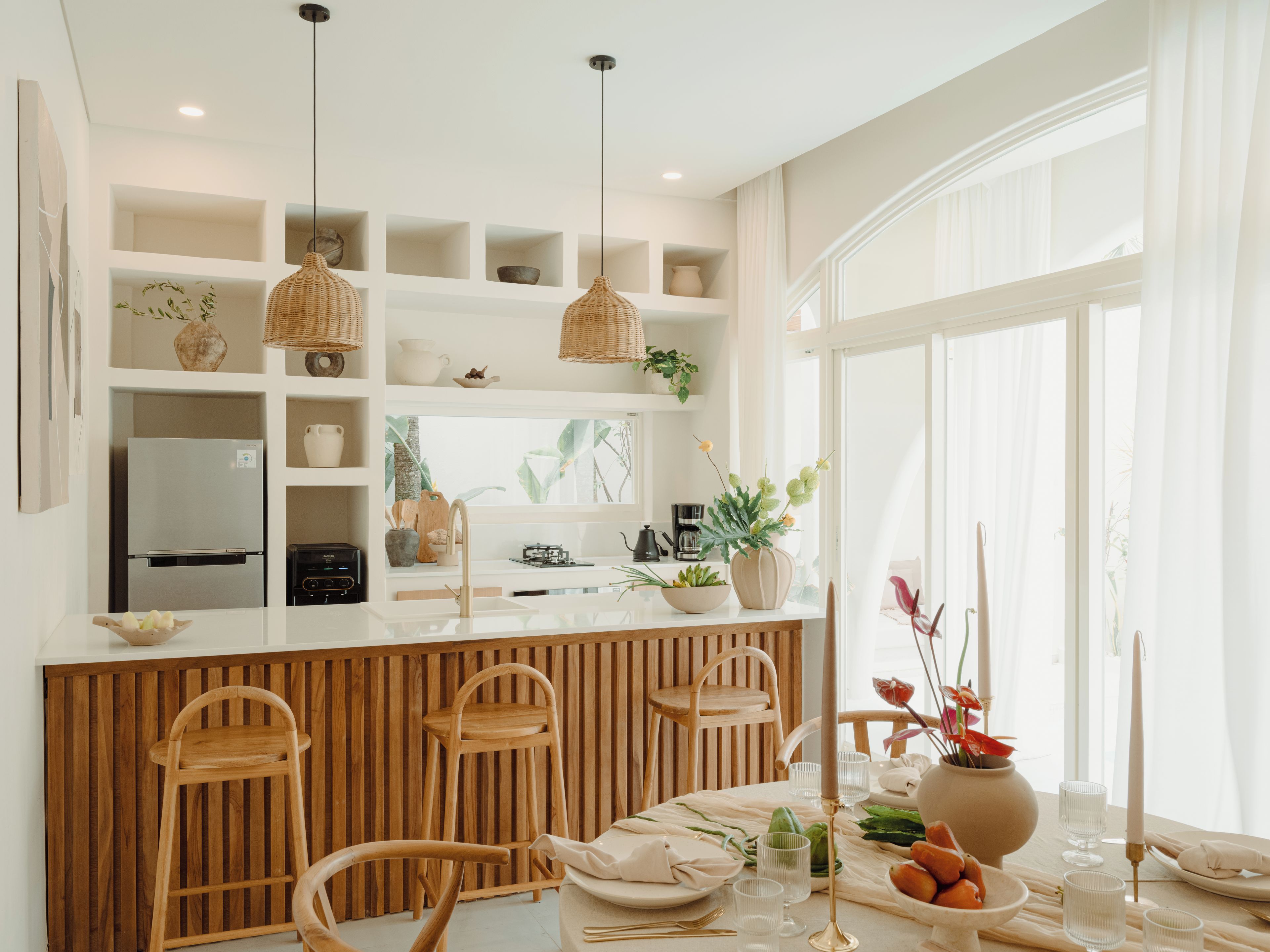 A modern kitchen with a central island, wooden chairs, and a dining table set for a meal.